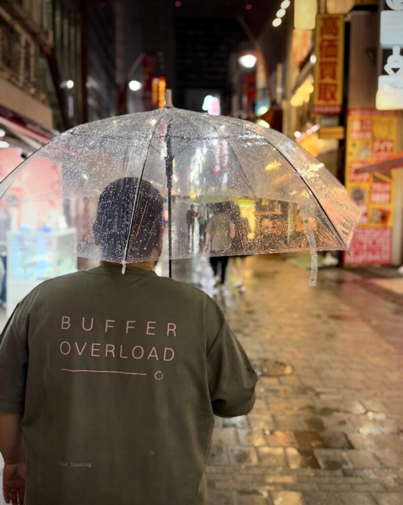 Camiseta oversize OC-03 de Ojo Cuidao! fotografiada bajo la lluvia en Tokio